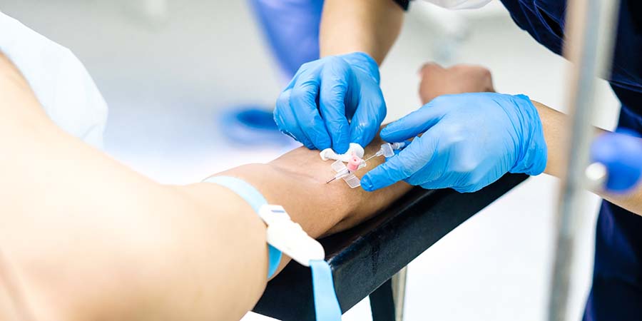 Nurse with blue gloves giving an IV to a patient